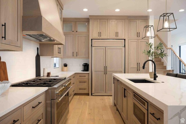 5346 Cyan Ln, St George, UT 84790 - kitchen with light stone counters, a sink, built in appliances, light wood-type flooring, and premium range hood