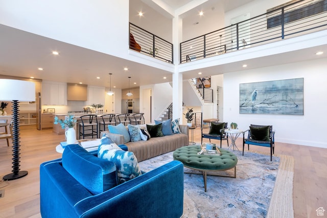 165 S Farmhouse Cir, Kaysville, UT 84037 - living room featuring recessed lighting, light wood-style flooring, a towering ceiling, baseboards, and stairs