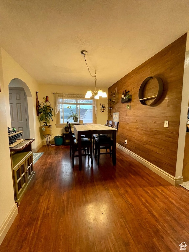 221 N 100 E, Price, UT 84501 - dining room featuring wooden walls, dark wood-style flooring, arched walkways, baseboards, and a chandelier