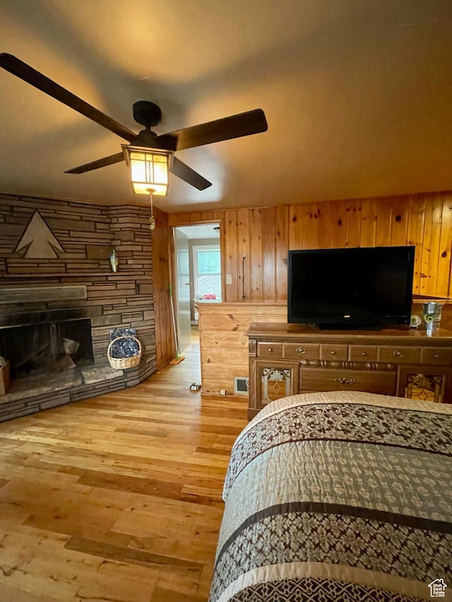 221 N 100 E, Price, UT 84501 - bedroom with light wood-type flooring, wooden walls, a stone fireplace, and a ceiling fan