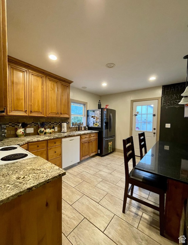 221 N 100 E, Price, UT 84501 - kitchen featuring dishwasher, black fridge, brown cabinets, decorative backsplash, and a sink