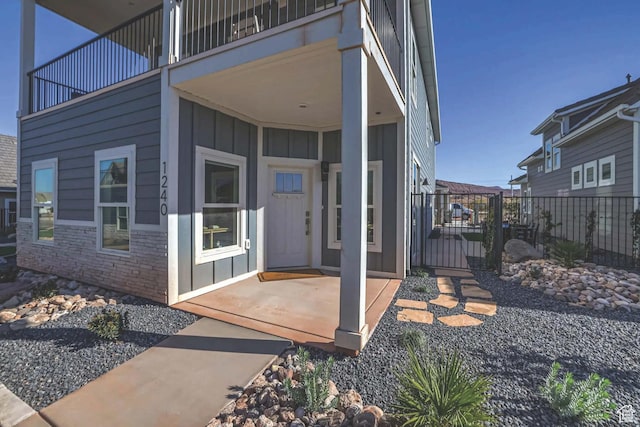 1240 E Villa Way Unit 64, Washington, UT 84780 - property entrance featuring board and batten siding, a patio area, fence, a balcony, and stone siding