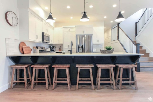 1240 E Villa Way Unit 64, Washington, UT 84780 - kitchen featuring light wood-style flooring, stainless steel appliances, a peninsula, light countertops, and tasteful backsplash