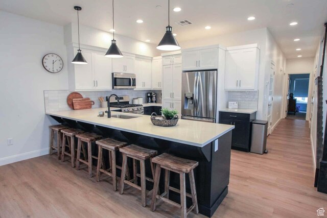 1240 E Villa Way Unit 64, Washington, UT 84780 - kitchen featuring a breakfast bar area, stainless steel appliances, a peninsula, light wood-style floors, and light countertops