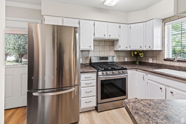 kitchen featuring a sink, dark countertops, appliances with stainless steel finishes, and white cabinetry