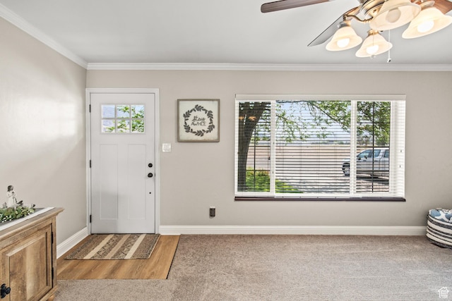 entryway with baseboards, carpet, ceiling fan, and crown molding