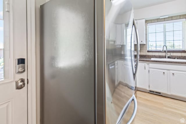 kitchen featuring visible vents, light wood finished floors, a sink, decorative backsplash, and white cabinetry