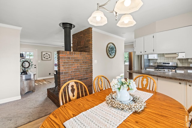 dining area featuring baseboards, ornamental molding, light carpet, a wood stove, and light wood-style floors