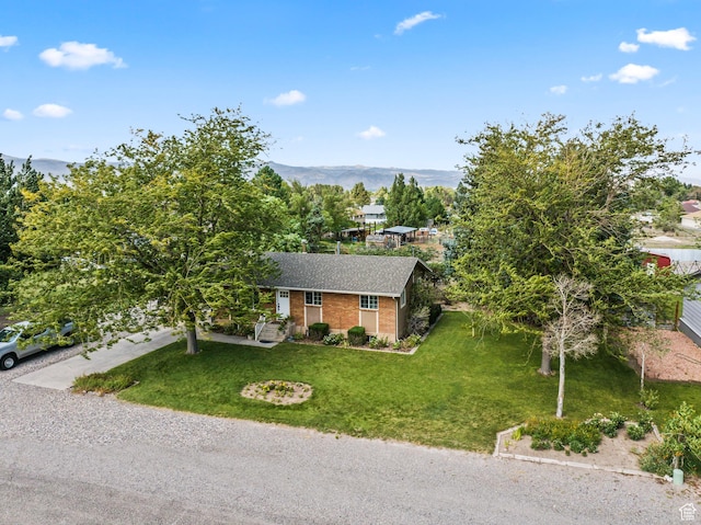 view of front of home featuring brick siding, a mountain view, a shingled roof, and a front lawn