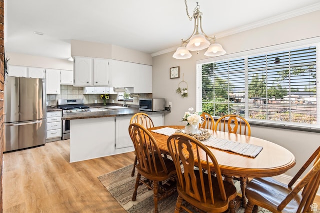dining space featuring light wood finished floors and ornamental molding