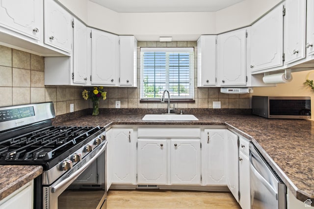kitchen featuring dark countertops, backsplash, appliances with stainless steel finishes, and a sink