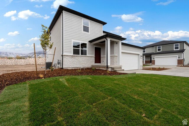 1264 N Berra Blvd Unit 133, Tooele, UT 84074 - view of front of property featuring a front lawn, brick siding, a garage, concrete driveway, and central air condition unit