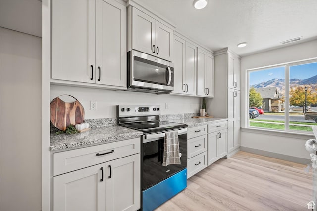 658 S 85 E Unit 13, Smithfield, UT 84335 - kitchen with appliances with stainless steel finishes, light wood finished floors, baseboards, a mountain view, and light stone counters
