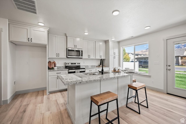 658 S 85 E Unit 13, Smithfield, UT 84335 - kitchen featuring stainless steel appliances, a sink, light wood-style flooring, an island with sink, and a kitchen breakfast bar
