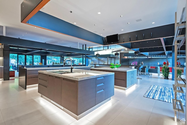 interior space featuring a spacious island, modern cabinets, light stone counters, and a sink