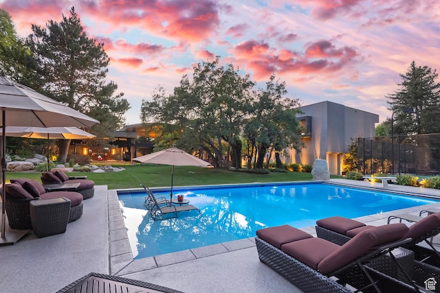 pool at dusk featuring an outdoor pool and a patio