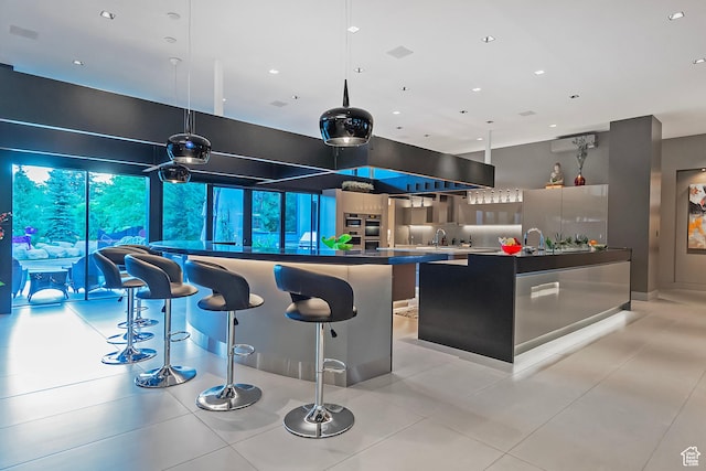 kitchen with modern cabinets, a kitchen island, a breakfast bar area, freestanding refrigerator, and a sink