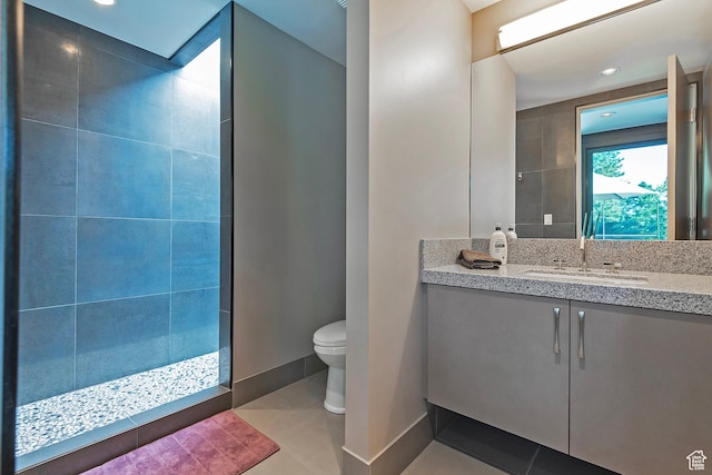 bathroom featuring baseboards, toilet, tile patterned flooring, walk in shower, and vanity