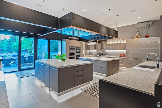 kitchen featuring light tile patterned floors, decorative backsplash, a spacious island, modern cabinets, and a sink