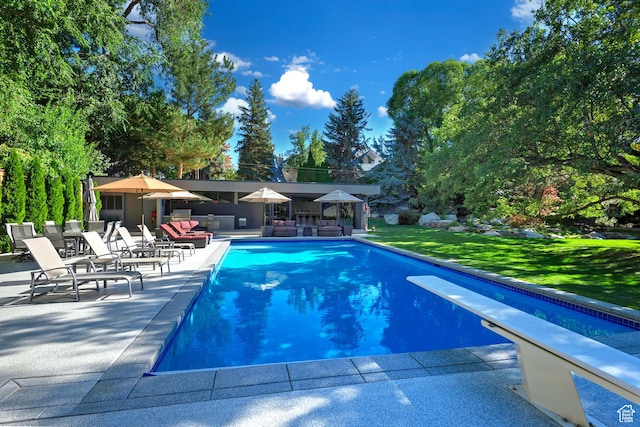 pool featuring a diving board, a yard, and a patio area
