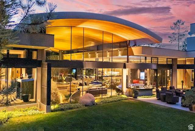 back of house at dusk with a lawn