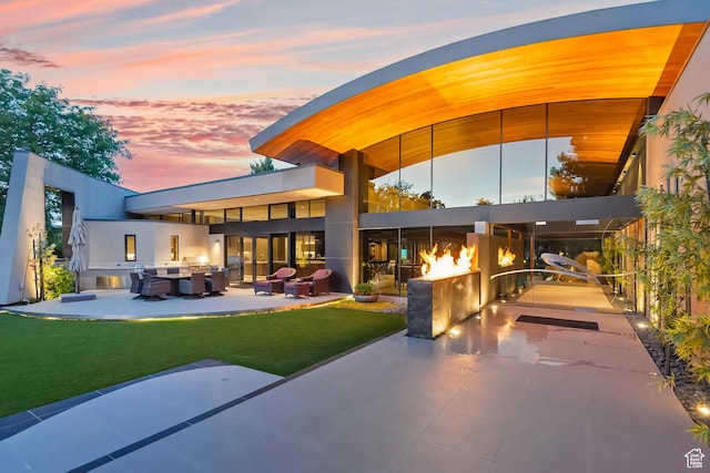back of house at dusk with an outdoor hangout area, a yard, and a patio area