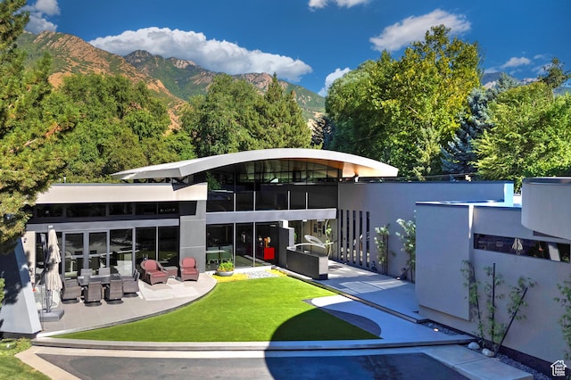back of house with a patio, a lawn, and a mountain view