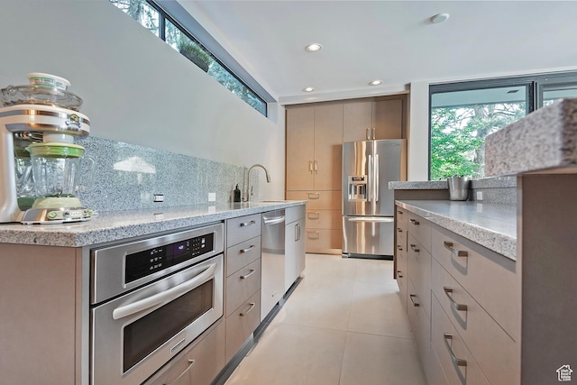 kitchen featuring light tile patterned floors, light stone counters, recessed lighting, stainless steel appliances, and tasteful backsplash