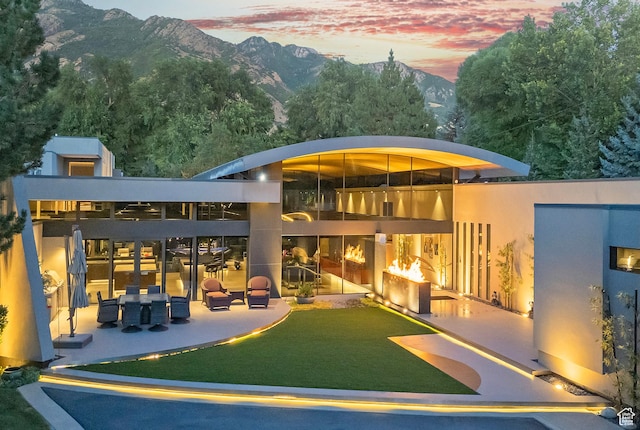 back of property at dusk with a mountain view and a patio