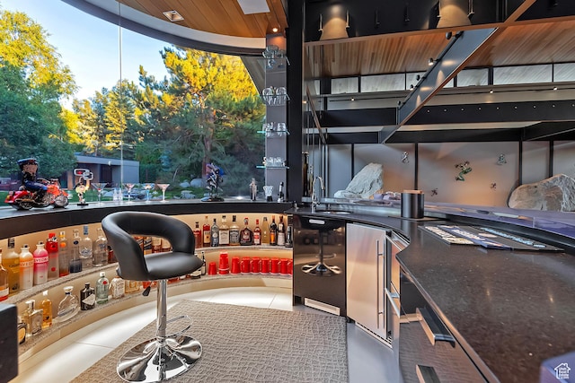interior space featuring tile patterned flooring, fridge, a sink, and a community bar