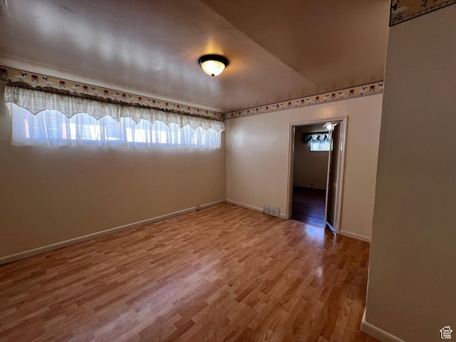 unfurnished room featuring baseboards, visible vents, and wood finished floors