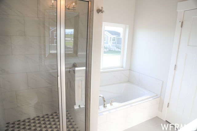bathroom featuring a shower stall and a bath
