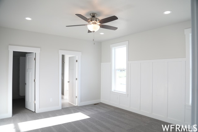 unfurnished bedroom with carpet, a ceiling fan, a wainscoted wall, and recessed lighting