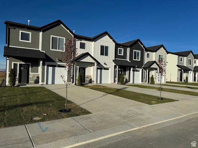 multi unit property with board and batten siding, a residential view, driveway, stone siding, and an attached garage