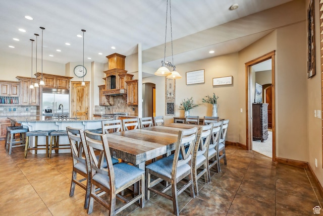 dining area featuring arched walkways, dark tile patterned floors, baseboards, and recessed lighting