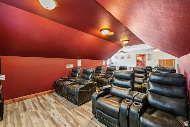 cinema with lofted ceiling, baseboards, a textured ceiling, a ceiling fan, and wood finished floors