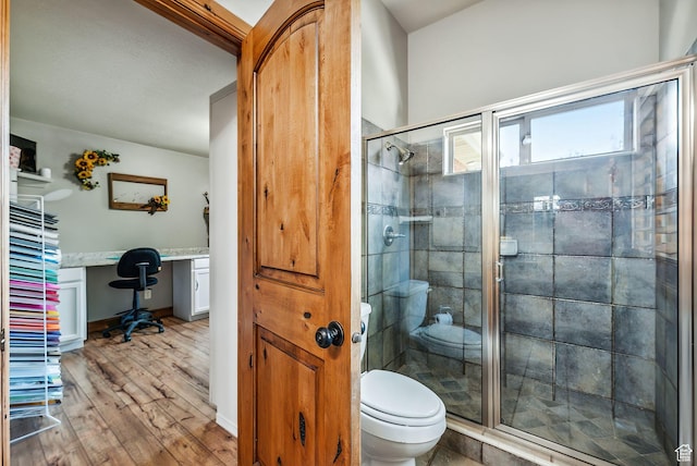 bathroom featuring baseboards, toilet, a shower stall, and wood finished floors