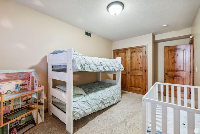 carpeted bedroom with a textured ceiling and visible vents
