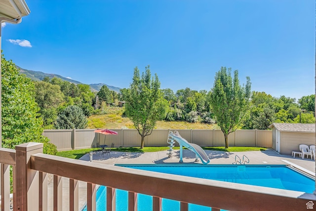 view of pool with a fenced backyard, a water slide, a mountain view, and a fenced in pool