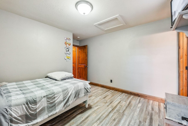 bedroom featuring baseboards, attic access, and light wood-type flooring