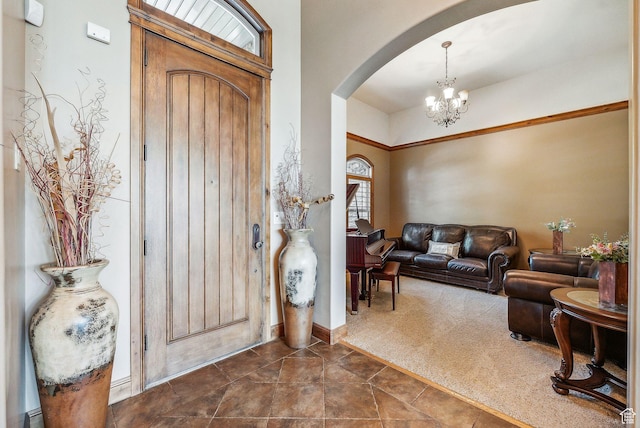 entrance foyer featuring arched walkways, a notable chandelier, and dark colored carpet