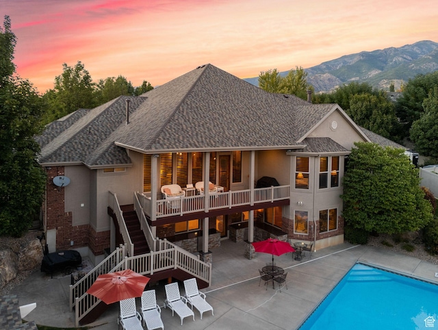 rear view of house with a patio area, stairway, stucco siding, outdoor dining space, and an outdoor pool