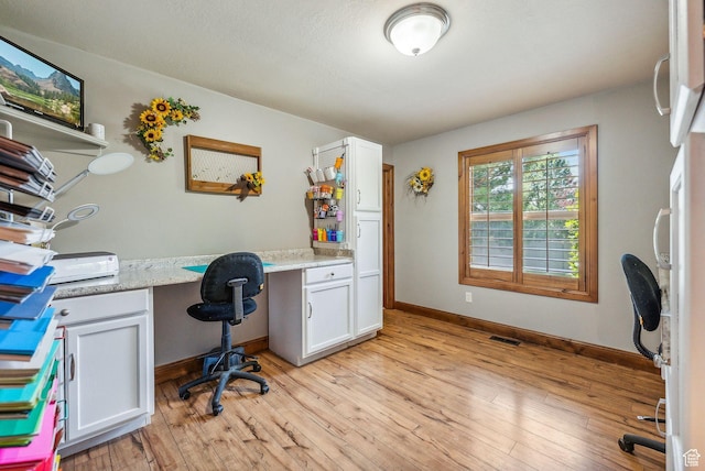 office area featuring baseboards, visible vents, built in desk, and light wood-style flooring