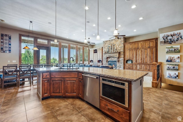 kitchen featuring plenty of natural light, ceiling fan, a kitchen island with sink, and stainless steel appliances