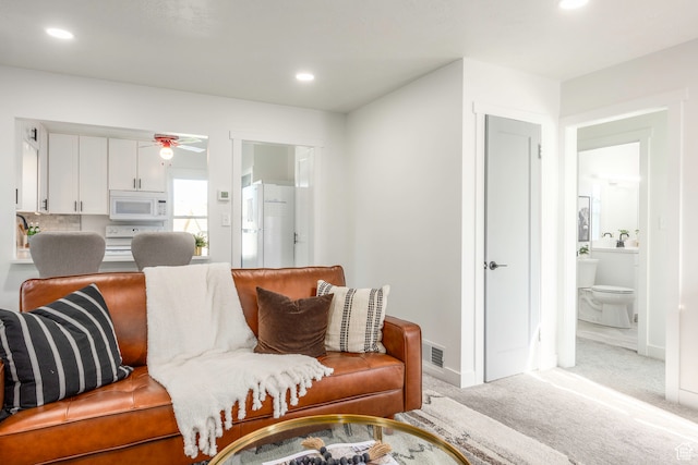 carpeted living room with ceiling fan