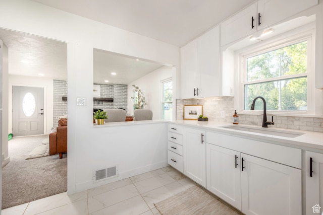 kitchen with backsplash, white cabinetry, light carpet, and sink