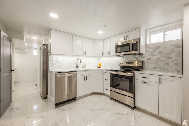 kitchen featuring light tile patterned floors, appliances with stainless steel finishes, tasteful backsplash, sink, and white cabinets