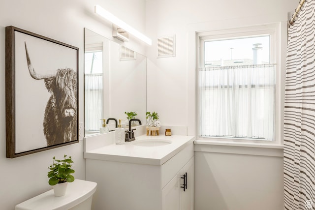 bathroom with toilet, plenty of natural light, and vanity