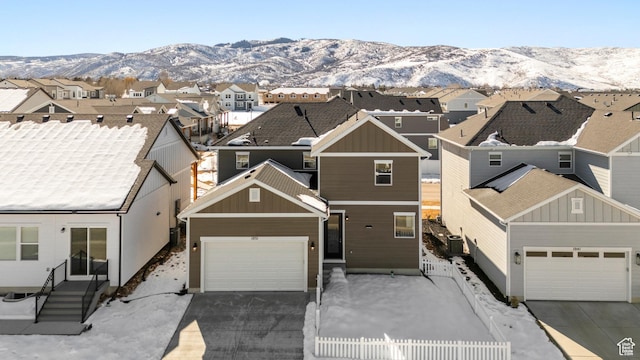 view of front of property featuring a mountain view, a residential view, concrete driveway, and fence