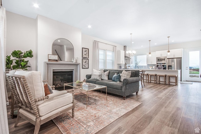 living room with recessed lighting, a notable chandelier, light wood-style floors, and a glass covered fireplace